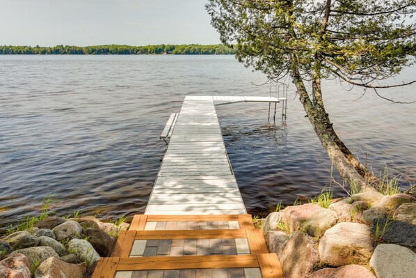 A wooden dock extending into calm water, surrounded by rocks and a tree. - Lakefront Pearson Cottage w/ Swim Dock + Kayaks! (Pearson)