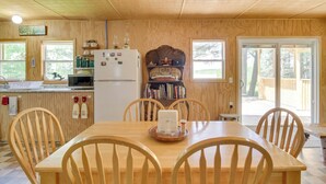 Un comedor con paneles de madera, una mesa, sillas, un refrigerador y una estantería.