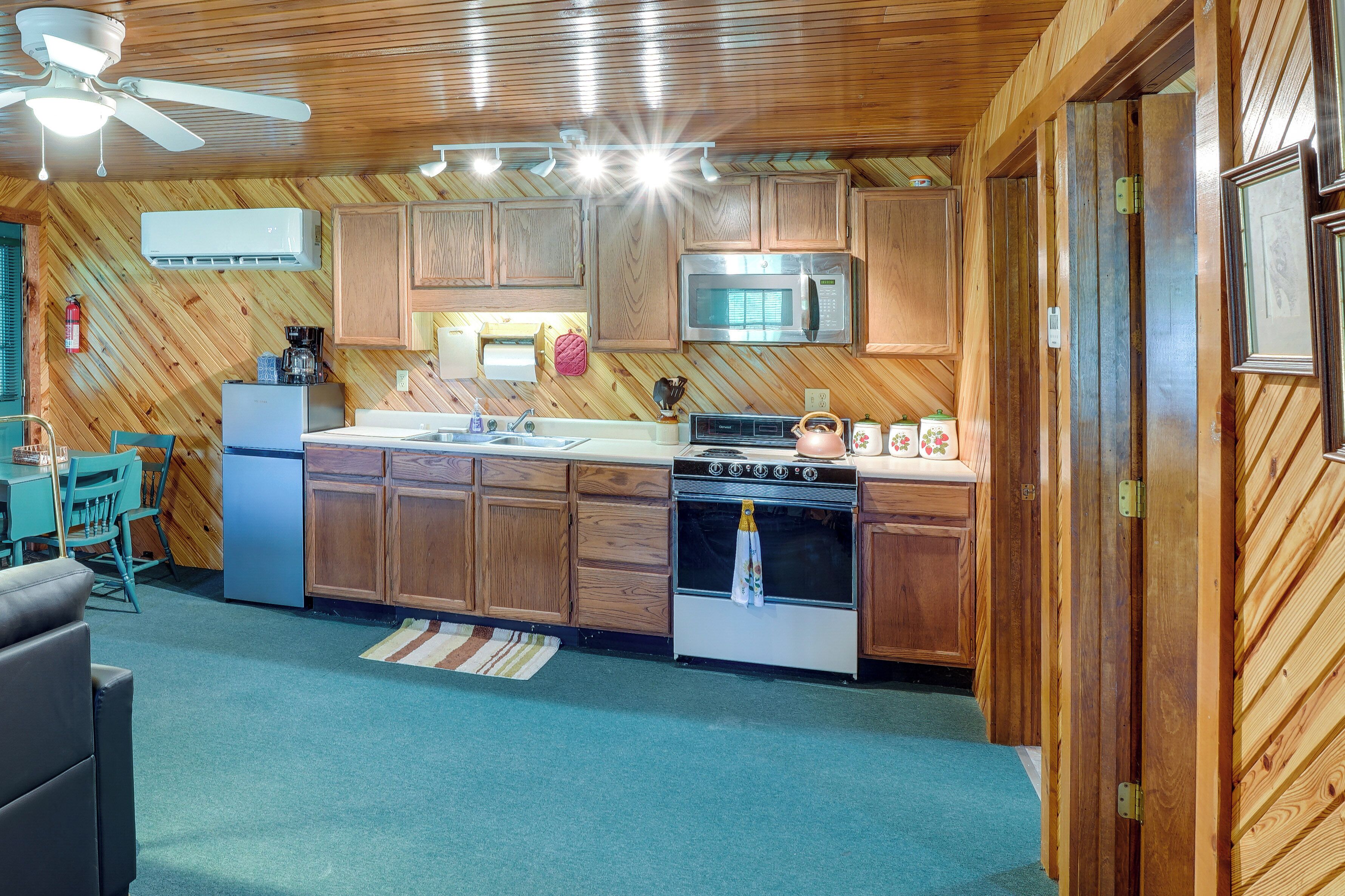 A kitchen with wooden cabinets, a microwave, a stove, and a ceiling fan.