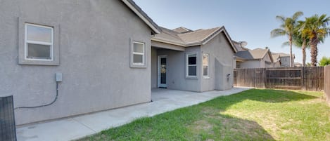 A residential house with a covered patio, a small front yard, and a wooden fence.