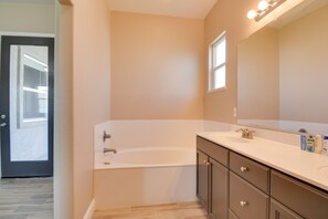 A modern bathroom with a bathtub, vanity, and mirror. - Remodeled Livingston Home w/ Private Backyard! (Livingston)