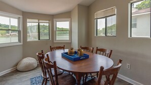 Comedor con una mesa redonda de madera, seis sillas y una bandeja azul con utensilios de cocina.