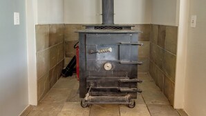 Una estufa de leña portátil en un rincón de una habitación con paredes y suelo de baldosas.