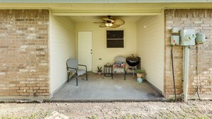 A covered porch with two chairs, a small table, a ceiling fan, and a grill. - Fenced Yard & Grill: San Juan Vacation Rental! (San Juan)