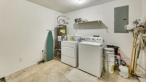 A laundry room with two stacked washers and dryers, a shelf above the dryers, a mop rack, and cleaning supplies. - Fenced Yard & Grill: San Juan Vacation Rental! (San Juan)