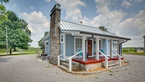 A single-story house with a stone chimney, light blue siding, and a red porch.