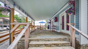 A covered porch with stone steps, wooden railings, and hanging flower baskets.