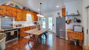 A kitchen with wooden cabinets, a large island, and a hanging pot rack.
