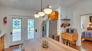 A kitchen with wooden cabinets, a microwave on a wooden stand, and a large island with a decorative centerpiece.