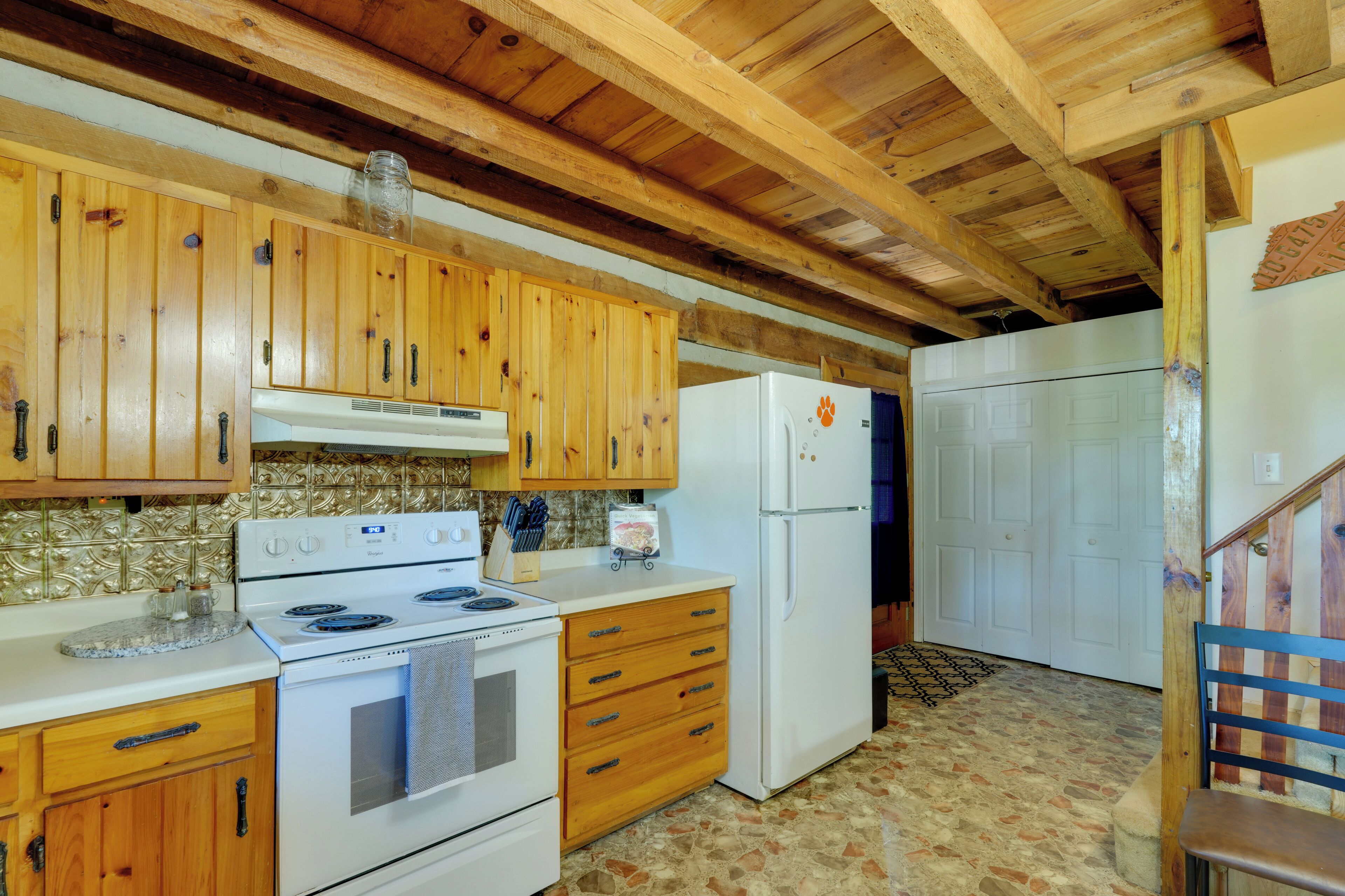 A kitchen with wooden cabinets, a stove, a refrigerator, and a tiled backsplash.