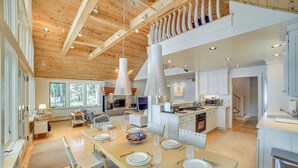 Una cocina amplia con una larga mesa de comedor, electrodomésticos modernos y un alto techo con vigas a la vista.