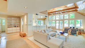 Un salón comedor espacioso con techo alto, ventanas amplias, cocina integrada y una zona de estar acogedora.