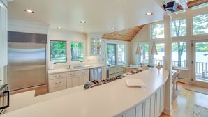 Una cocina moderna con una isla grande, electrodomésticos de acero inoxidable y ventanas amplias.