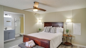 A bedroom with a bed, bedside lamps, a ceiling fan, a bedside table with a plant, and a bathroom with a sink and mirror. - Fire Pit + Deck: Peaceful Silver Creek Retreat (Silver Creek)