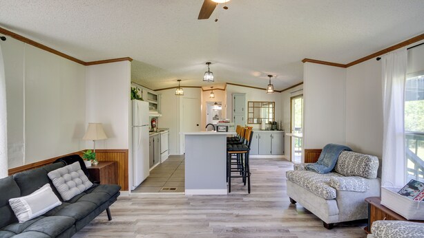 A spacious living area with a sofa, a patterned armchair, and a kitchen in the background. - Fire Pit + Deck: Peaceful Silver Creek Retreat (Silver Creek)
