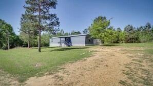 A single-story building with a covered outdoor area, surrounded by trees and grassy terrain. - Fire Pit + Deck: Peaceful Silver Creek Retreat (Silver Creek)