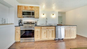 Une cuisine moderne avec des meubles en bois, des appareils électroménagers en acier inoxydable et un plancher en bois.