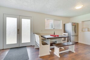 A kitchen with a dining table, bench, refrigerator, and double doors. - Rural Mountain-view Home Near Hiking + Off-roading (Tabiona)