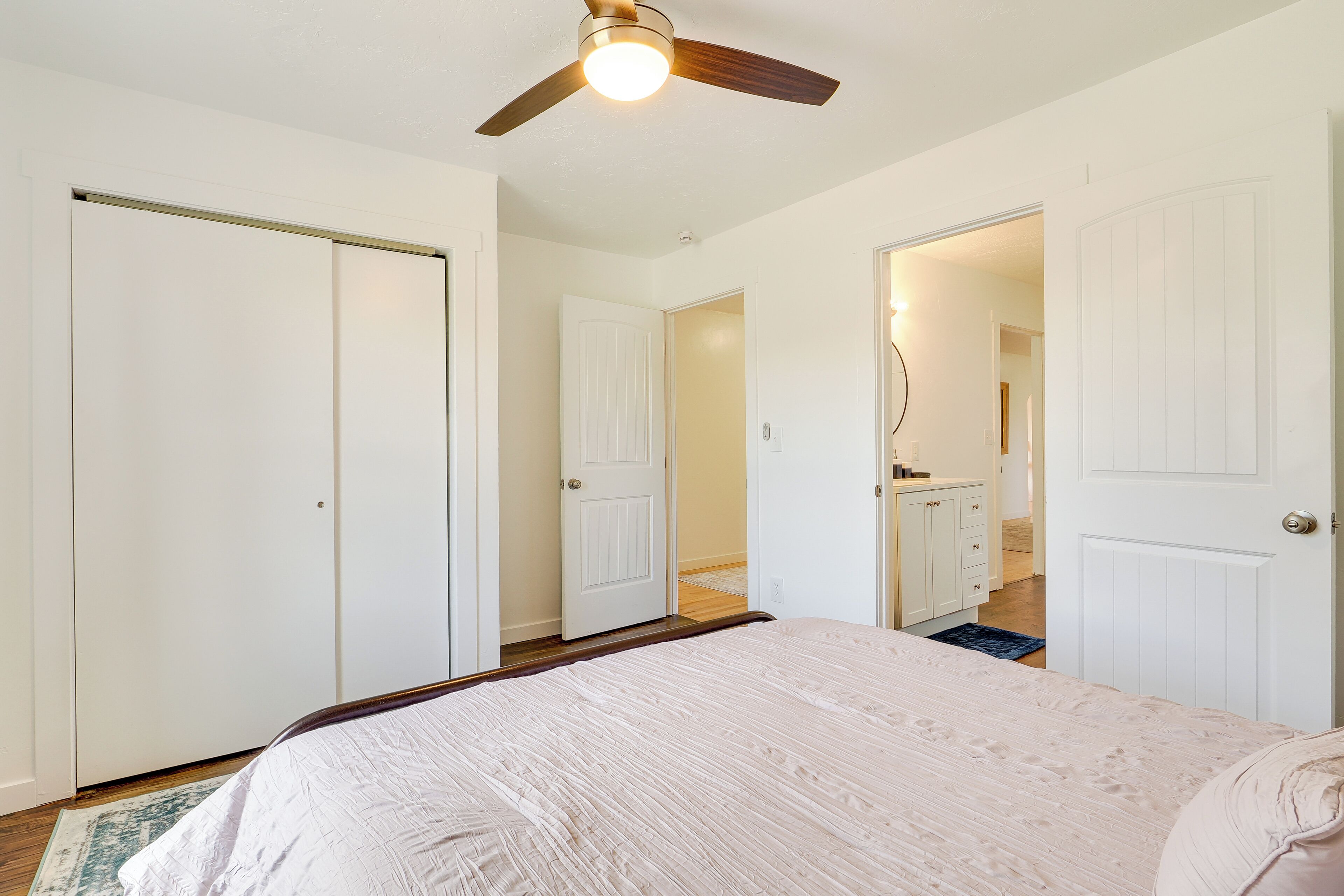 A bedroom with a bed, a ceiling fan, and white doors.