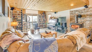 A cozy living room with a fireplace, bookshelves, a comfortable sofa, and a staircase leading to an upper level.