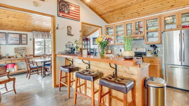 A spacious kitchen with wooden cabinets, a stainless steel refrigerator, and a bar area with stools.