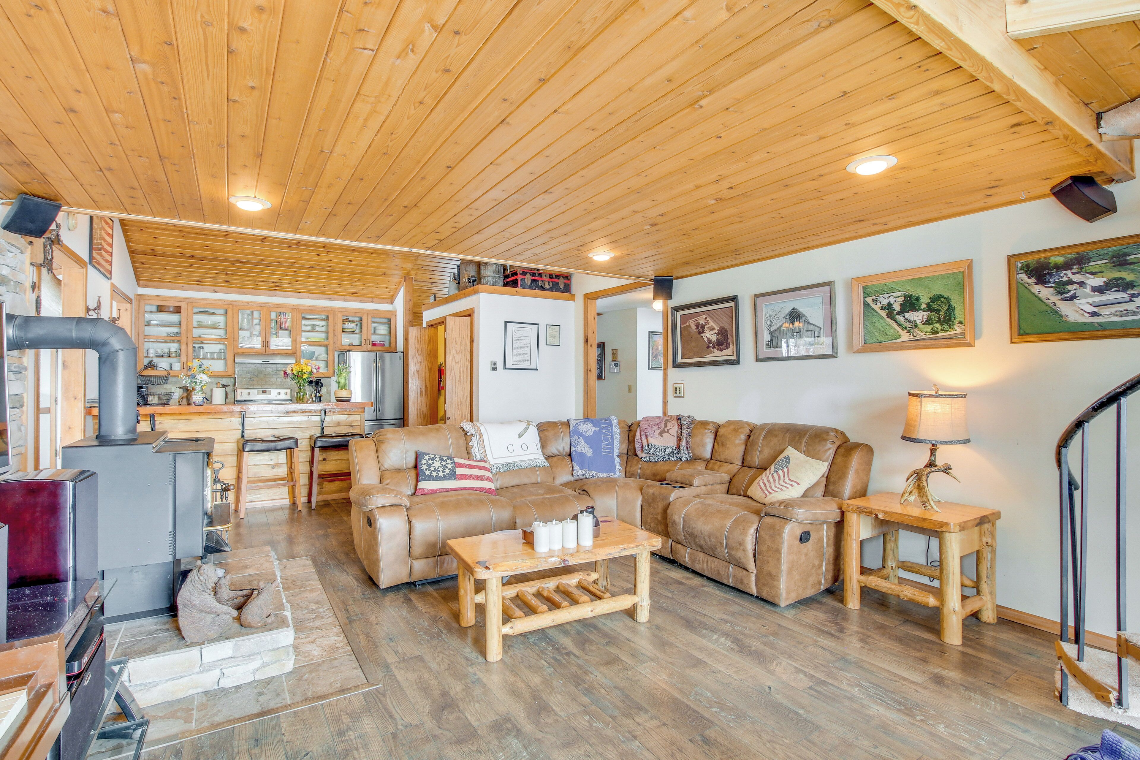 A cozy living room with a fireplace, wooden furniture, and a kitchen in the background.
