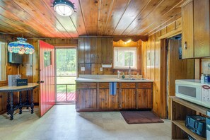 A wooden cabin interior with a kitchen area, including a countertop, sink, and microwave.