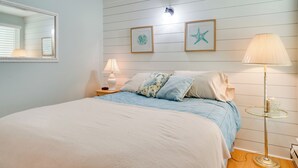 Een slaapkamer met een bed, twee nachtkastjes, een lamp en decoratie aan de muur.