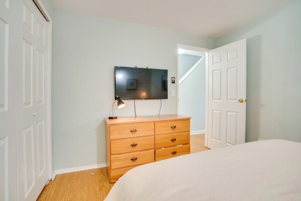 A bedroom with a bed, a dresser, a television, and a door.