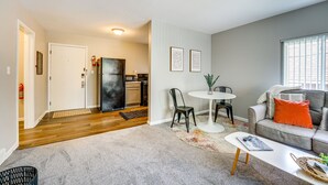 Una sala de estar con un sofá gris, una mesa de centro y un comedor con una mesa pequeña y sillas.