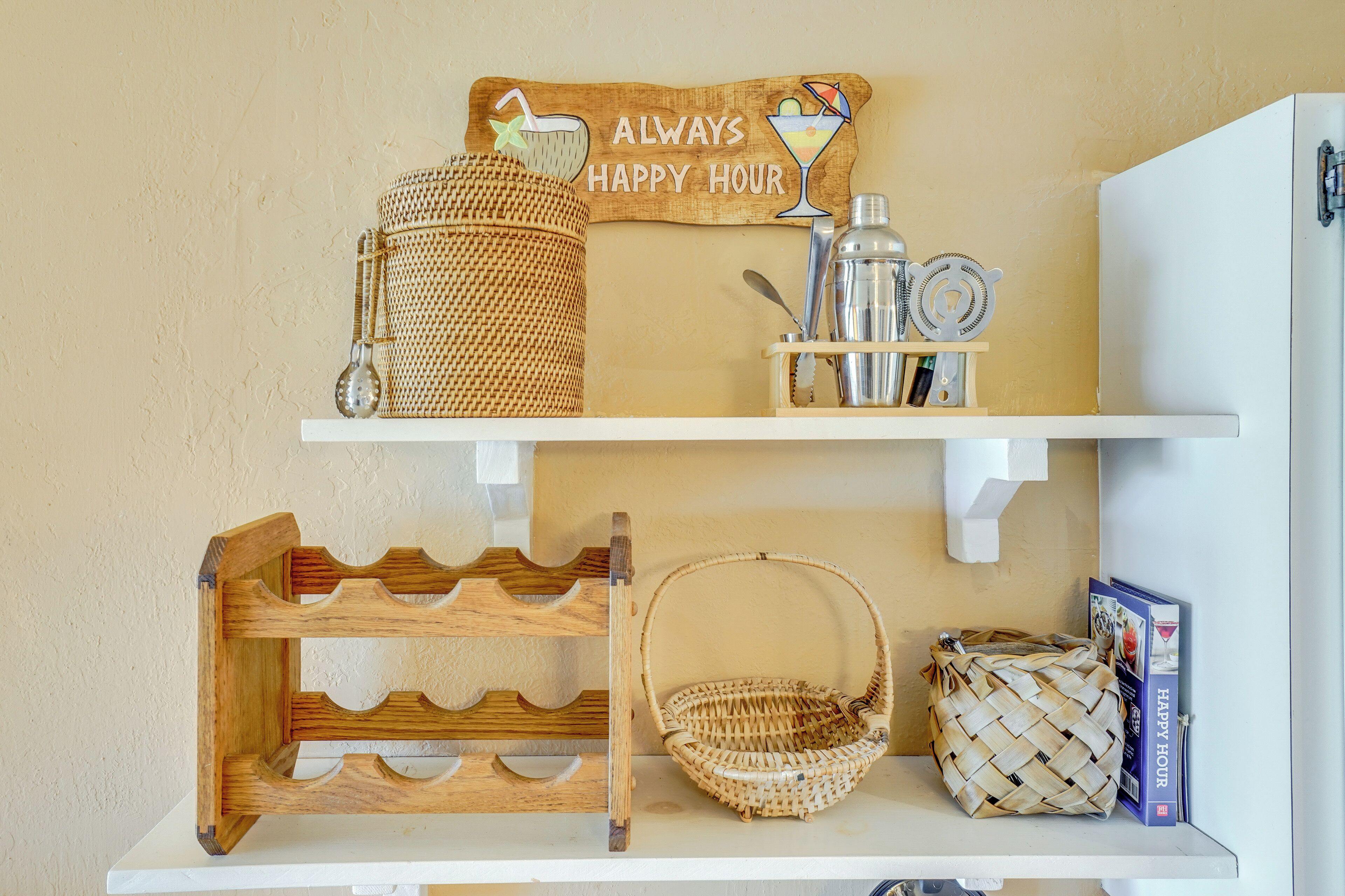 A shelf with a woven basket, a metal container, and a sign that reads "ALWAYS HAPPY HOUR".