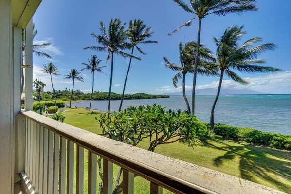 A balcony with a view of a tropical landscape, including palm trees and a body of water. - Kaunakakai Condo w/ Private Lanai & Ocean Views! (Kaunakakai)