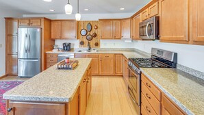 A kitchen with wooden cabinets, stainless steel appliances, granite countertops, and pendant lighting. - Wfh-friendly Columbiana Vacation Rental w/ Deck! (Columbiana)