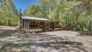 Eine rustikale Holzhütte mit Veranda, umgeben von Bäumen.
