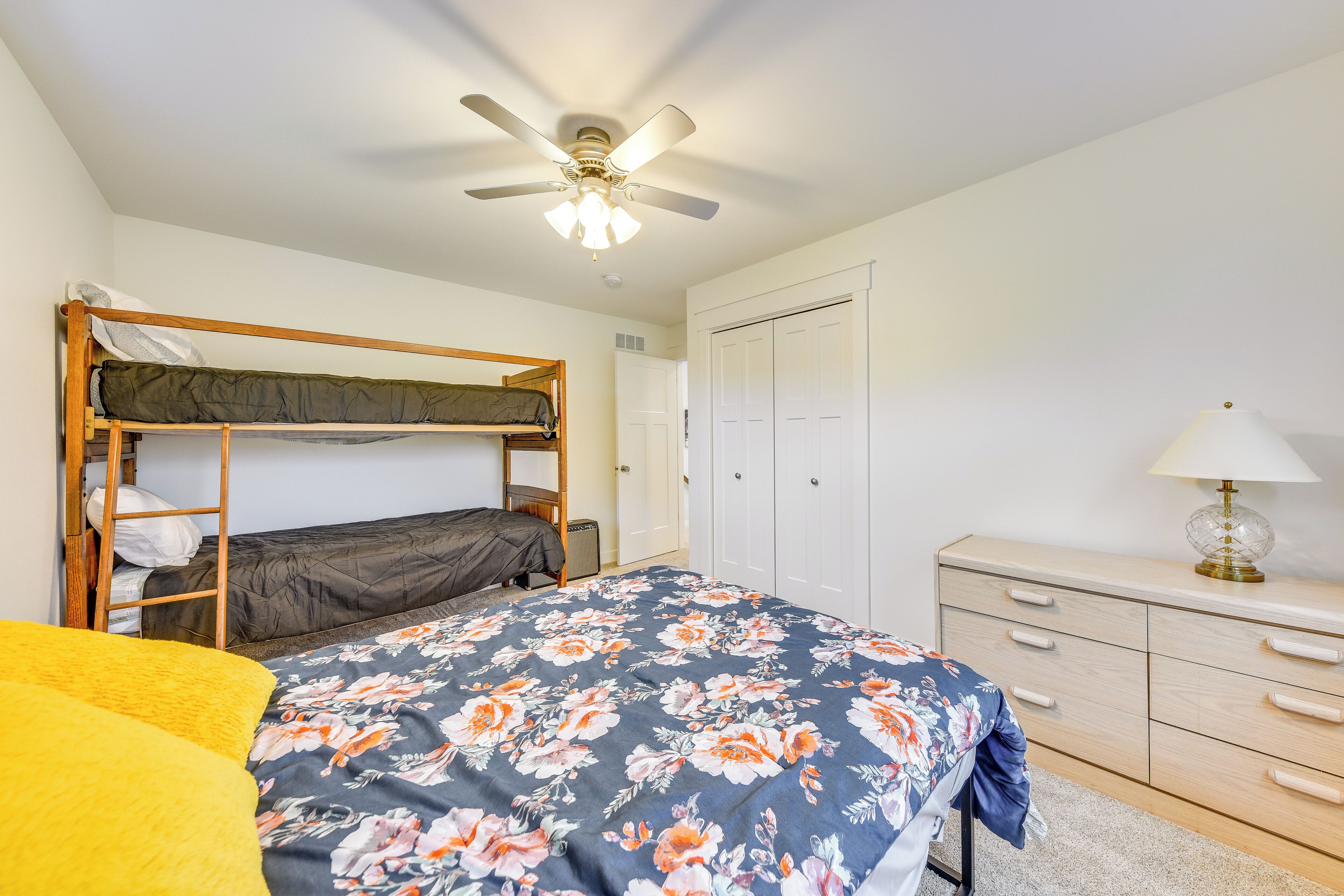A bedroom with a bunk bed, a desk with drawers, a lamp, and a ceiling fan.
