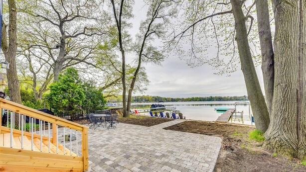 A paved deck with a wooden staircase leading to a terrace overlooking a lake. - Lakefront Burlington Vacation Rental: Dock + Beach (Burlington)