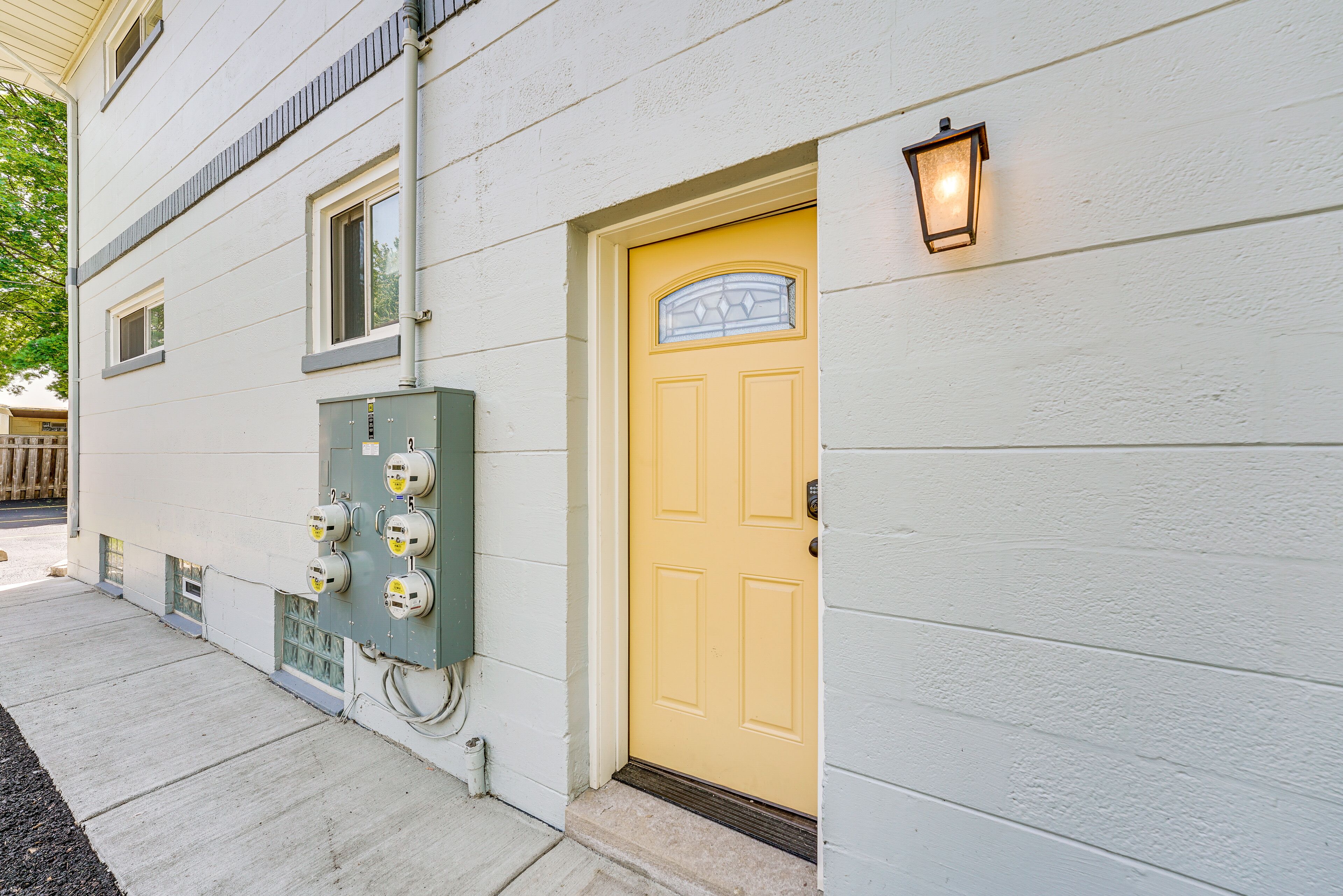 A building with a yellow door, a green electrical box, and a wall-mounted light fixture.