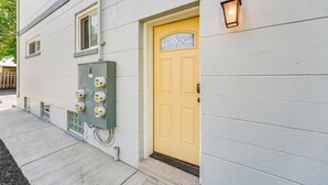A building with a yellow door, a green electrical box, and a wall-mounted light fixture. - Wyandotte Vacation Rental Apartment Near Hospital! (Wyandotte)