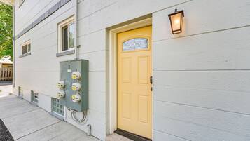A building with a yellow door, a green electrical box, and a wall-mounted light fixture.