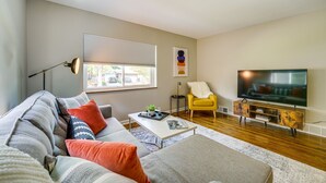 A living room with a sofa, coffee table, TV, and a yellow chair. - Wyandotte Vacation Rental Apartment Near Hospital! (Wyandotte)