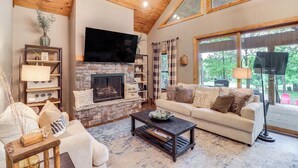 A cozy living room with a stone fireplace, a flat-screen TV, a sofa, and a coffee table. - Gorgeous Drasco Home Near Greers Ferry Lake! (Drasco)