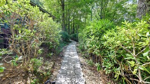 A stone pathway surrounded by lush greenery and trees. - Near Highlands: 36-acre Scaly Mountain Lodge (Scaly Mountain)