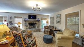 A cozy living room with a fireplace, comfortable seating, and a television. - Near Highlands: 36-acre Scaly Mountain Lodge (Scaly Mountain)