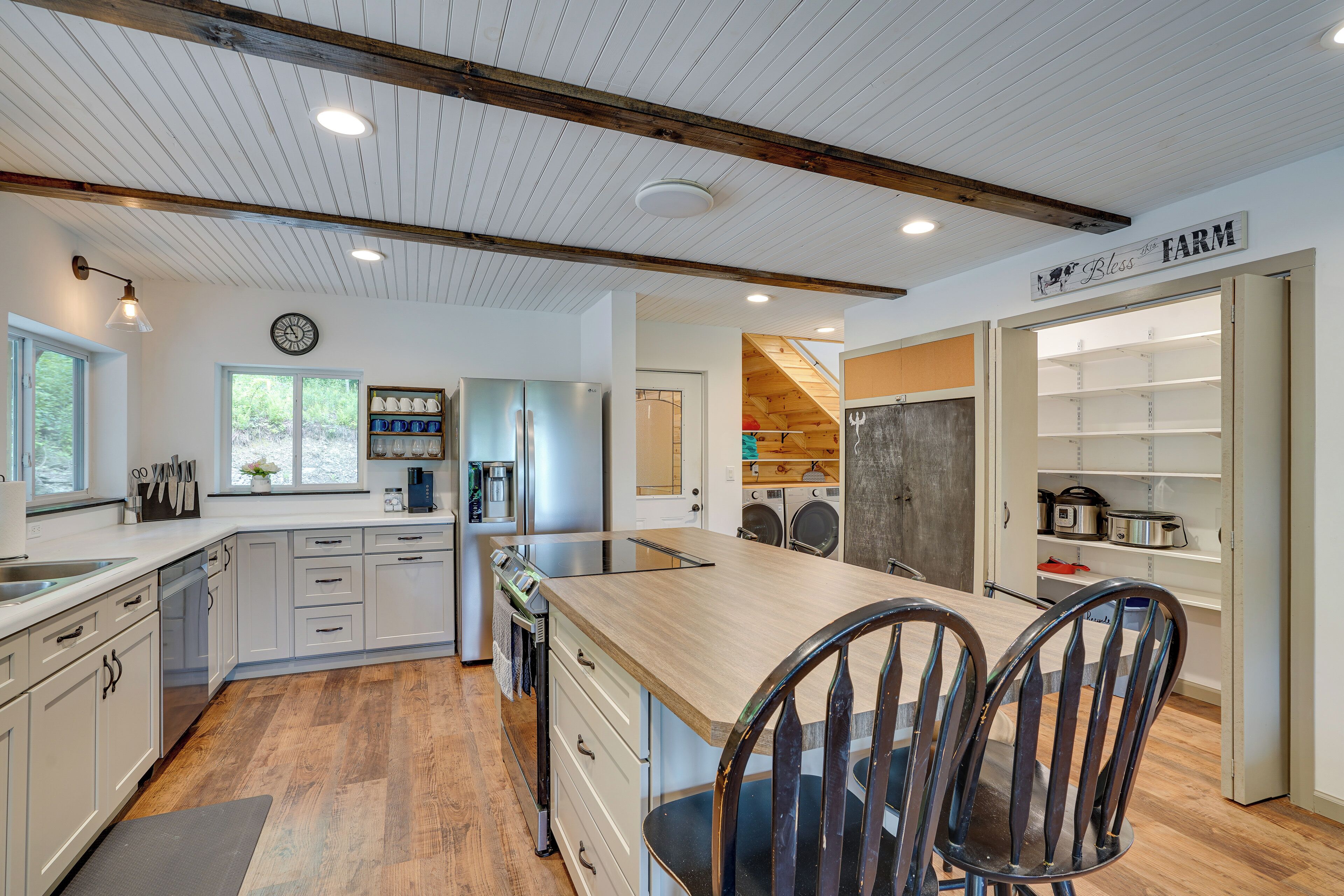 A modern kitchen with wooden countertops, stainless steel appliances, and a farmhouse-style ceiling.