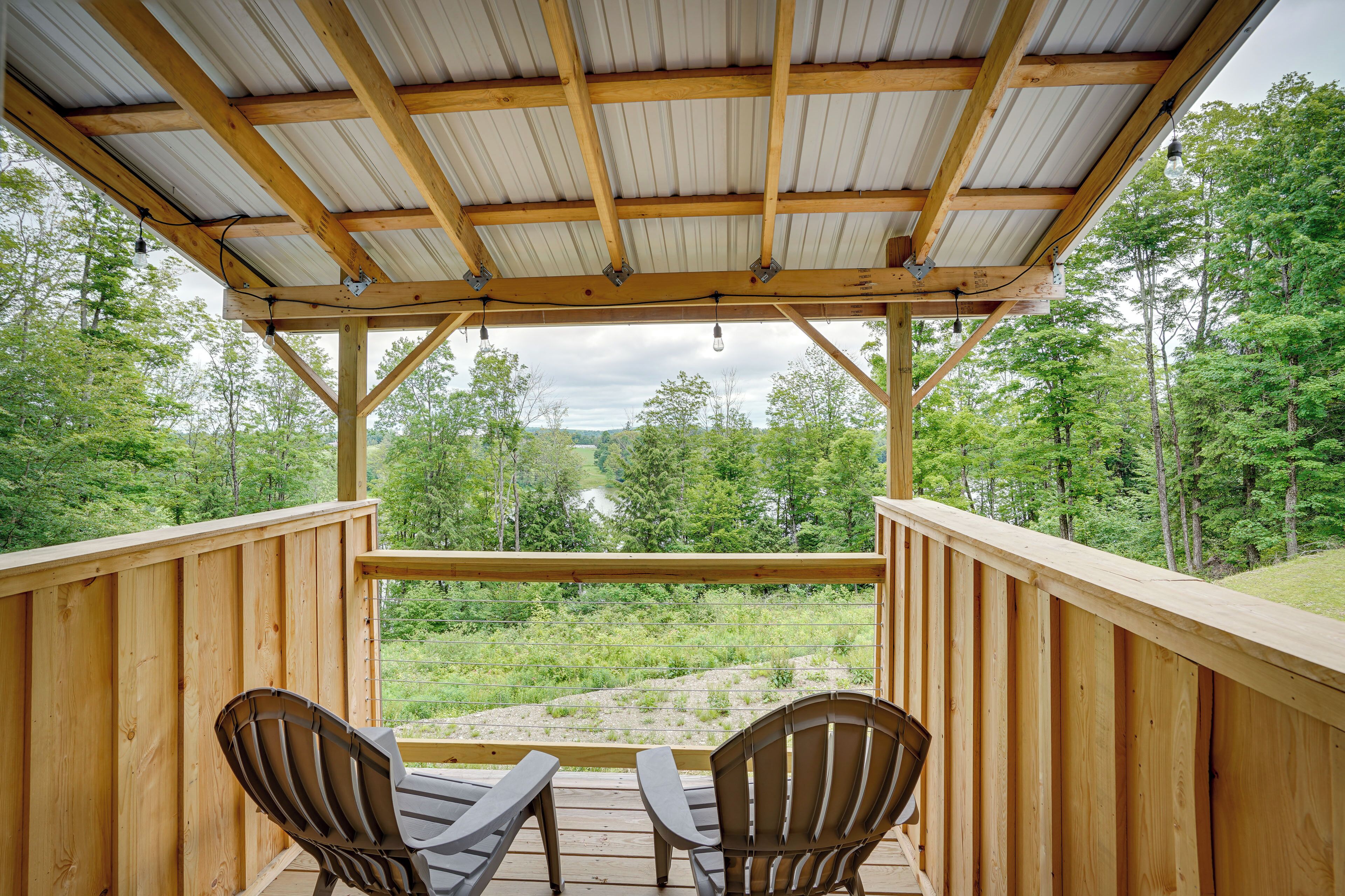 Una terraza de madera con dos sillas Adirondack que miran hacia un paisaje boscoso.
