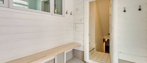 A room with a wooden bench, a white door, and a tiled floor.