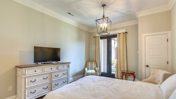 A bedroom with a large bed, a dresser, a television, and a chair near a window. - Loretto Vacation Rental w/ Community Resort Perks (Loretto)