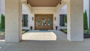 A covered entrance with a brick facade, double doors, and a clear pathway leading to the entrance. - Loretto Vacation Rental w/ Community Resort Perks (Loretto)