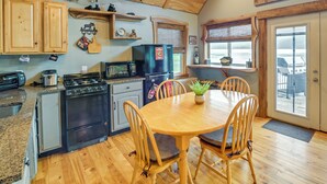 Una cocina con armarios de madera, estufa, refrigerador y una mesa de comedor con sillas.