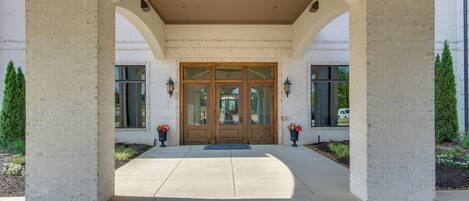 A covered entrance with a brick facade, double doors, and a clear pathway leading to the entrance.